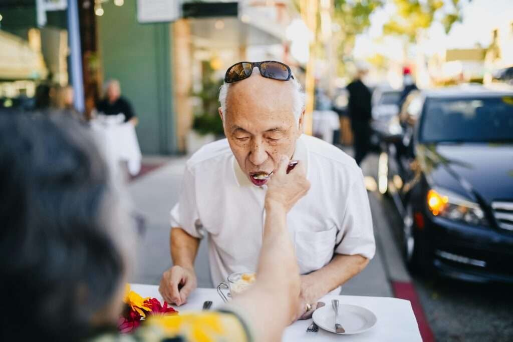 Senior couple sharing a sweet moment at a street café, enjoying leisure time outdoors.