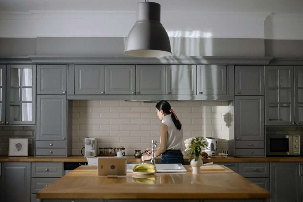 Woman cooking in a contemporary kitchen with gray cabinets and wooden countertops.